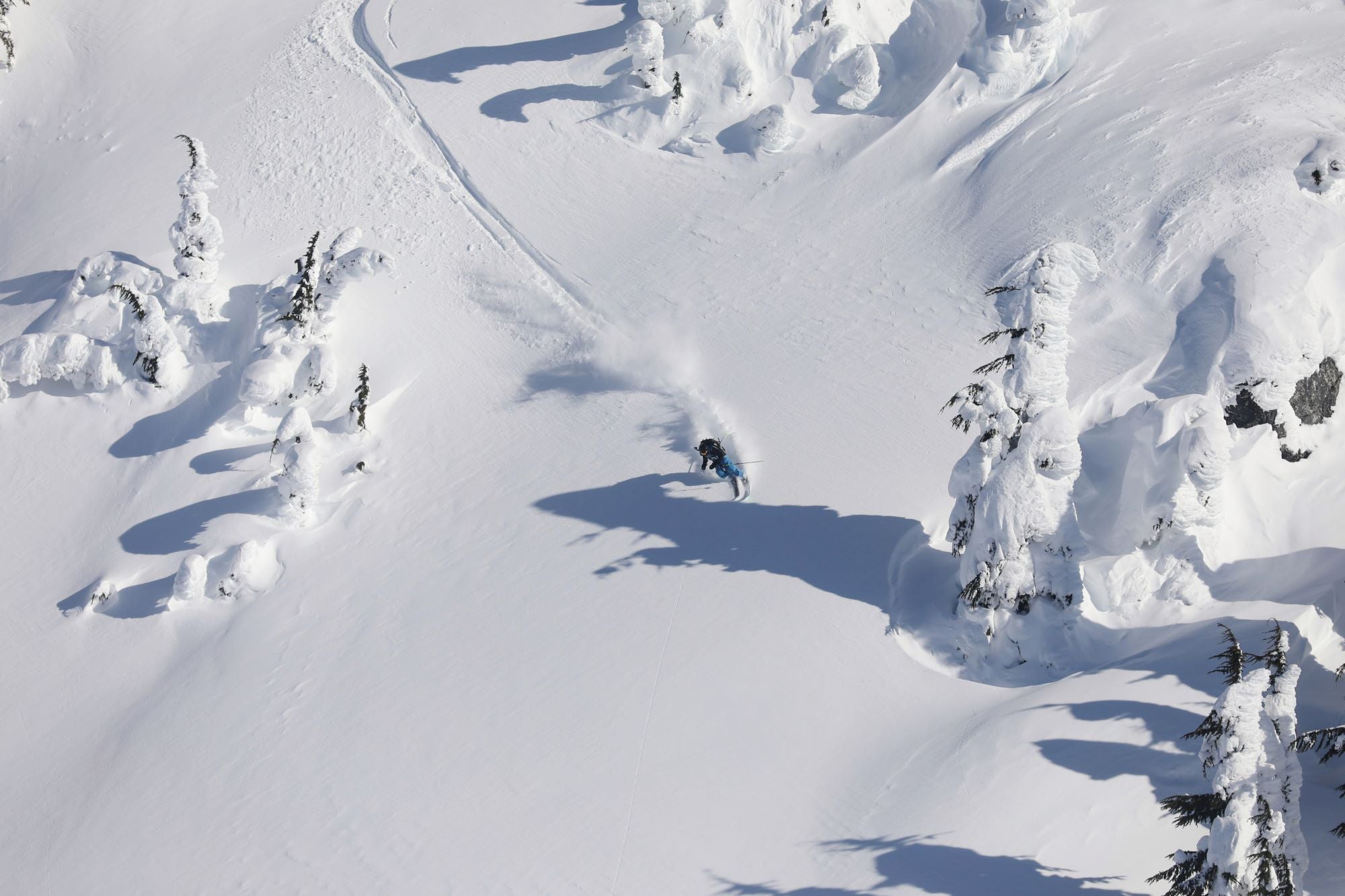 A freerider riding DOWN skis down a mountain in British Columbia.
